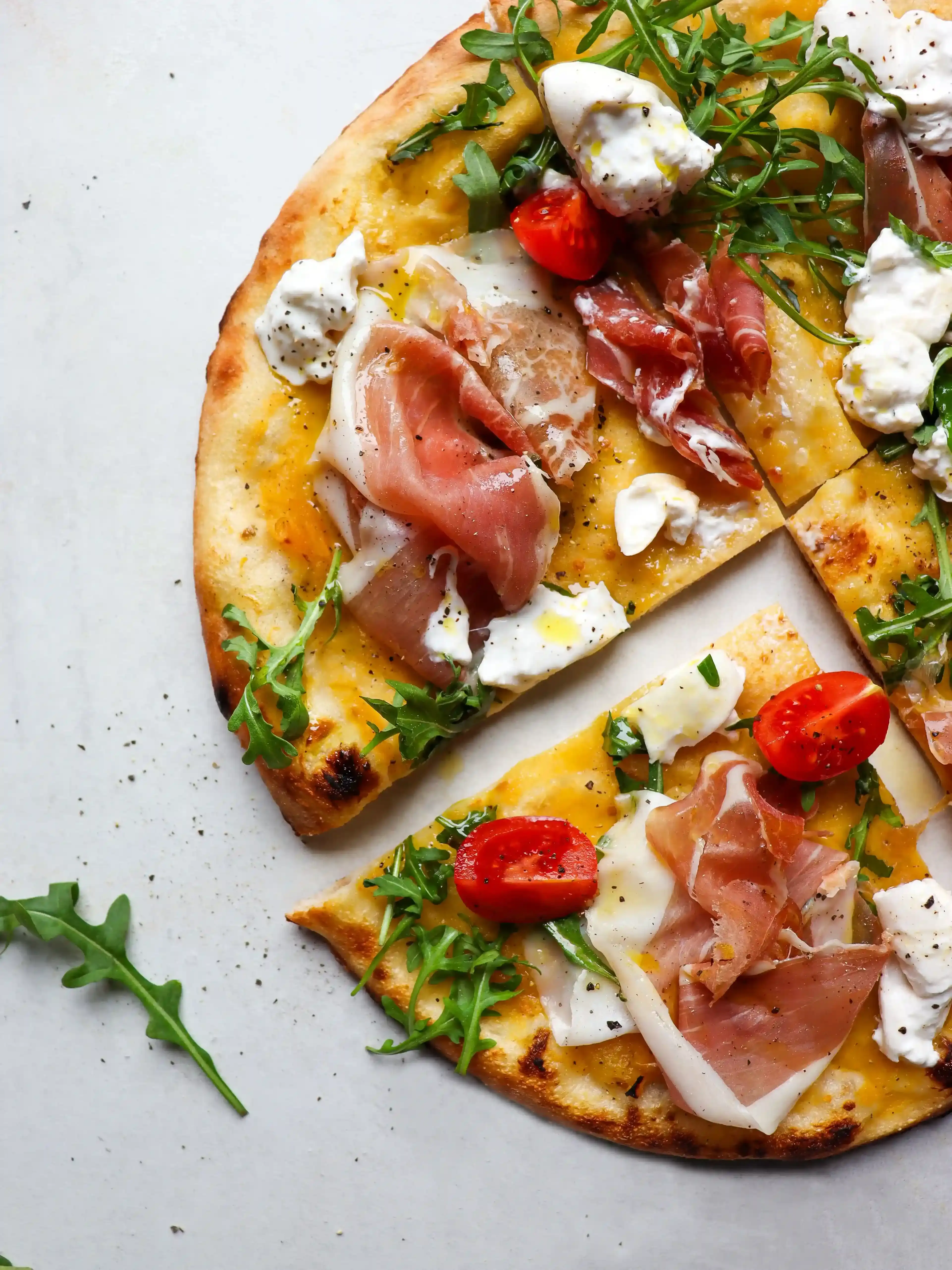 pizza mit gelber Tomatensoße und prosciutto crudo