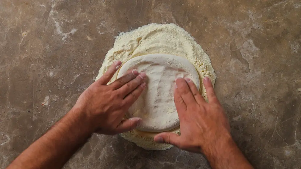 Pizzateiglinge im Semola-Bett langsam von innen nach außen arbeiten.