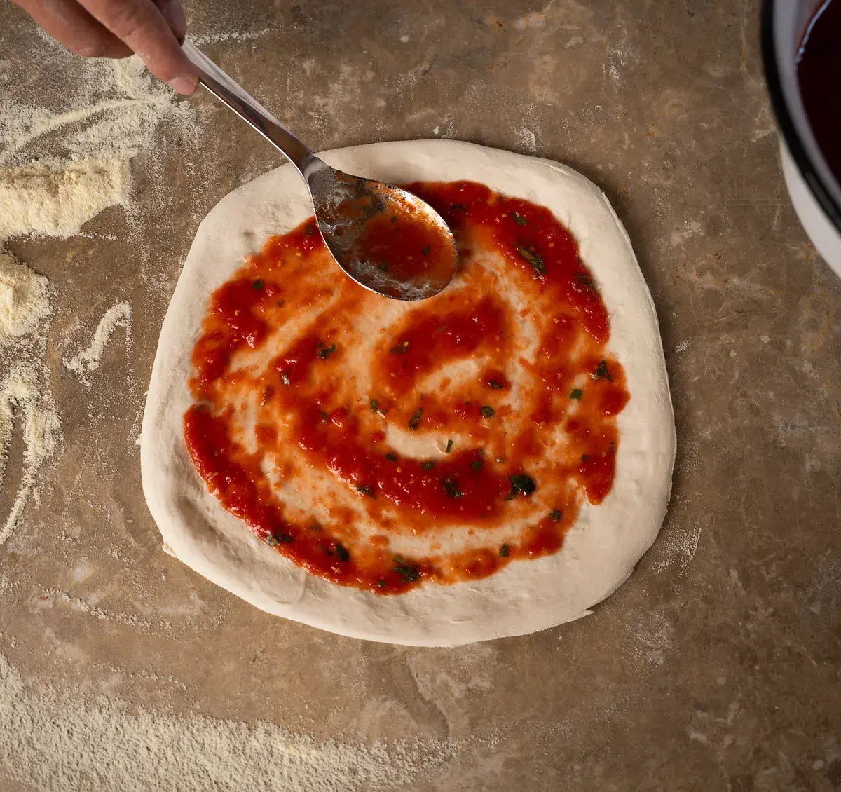 Tomatensoße wird auf Pizza verteilt