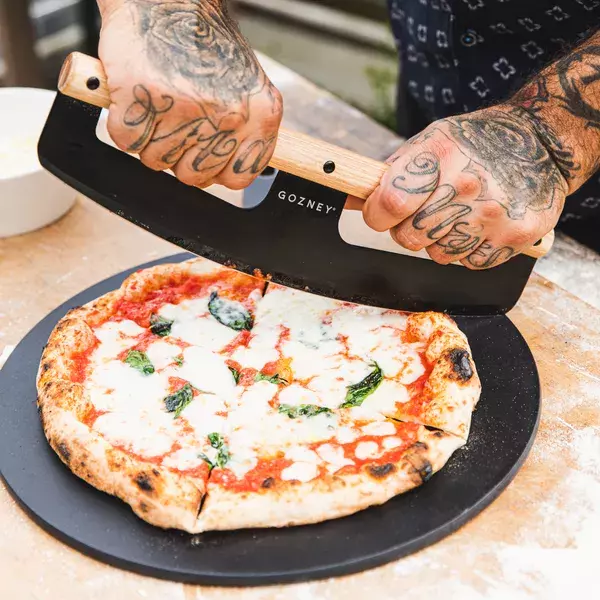 Bild von frischer neapolitanischer Pizza die mit Wiegemesser geschnitten wird